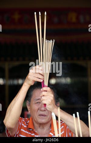 Lian Shan Shuang Lin, monastère. Un Chinois priant et offrant de l'encens. Adorateur bouddhiste. La combustion d'encens. Singapour. Banque D'Images