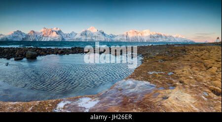 Panorama de la mer congelés et des sommets enneigés à l'aube entourée de rochers recouverts de glace, Djupvik, Alpes de Lyngen, Troms, Norvège Banque D'Images