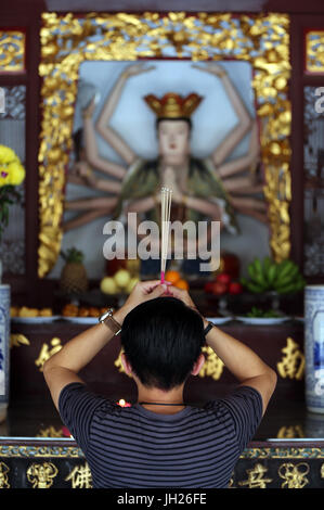 Temple Thian Hock Keng. Un jeune homme chinois priant et offrant de l'encens. Adorateur bouddhiste. La combustion d'encens. Homme qui prie. Singapour. Banque D'Images