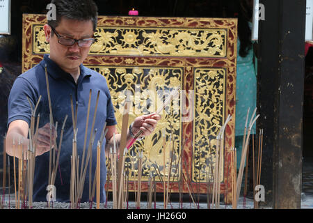 Temple Thian Hock Keng. Un Chinois priant et offrant de l'encens. Adorateur bouddhiste. La combustion d'encens. Singapour. Banque D'Images