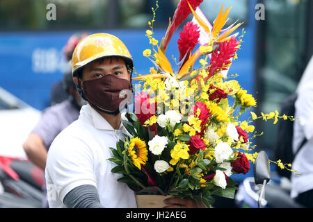 L'homme avec des fleurs riding a motorcycle sur Saigon Street. Le Vietnam. Banque D'Images