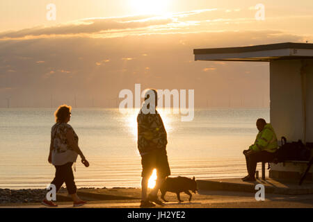 Un pêcheur et un couple appréciant la météo et le lever du soleil à l'coatal station balnéaire de Llandudno dans le Nord du Pays de Galles, Royaume-Uni Banque D'Images