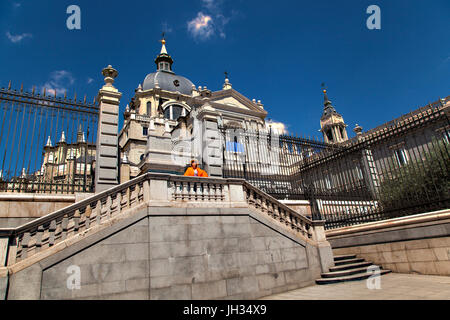 Femme portant haut orange vif sur les étapes de la cathédrale de la Almudena à Madrid Espagne , avec un ciel bleu au-dessus Banque D'Images