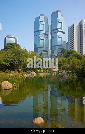 Les gens qui marchent autour d'un lac à Hong Kong Park entouré de grands immeubles de bureaux à Hong Kong, Chine. Banque D'Images