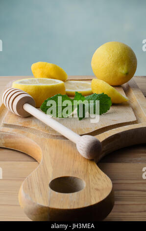 Ensemble et les tranches de citrons avec les feuilles de menthe et de miel drizzler sur planche en bois table de cuisine en pin ci-dessous. Banque D'Images