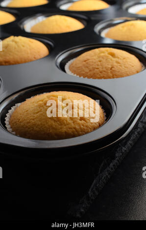 Des golden cupcakes, juste enlevé du four. En cas de papier noir iinside bun tin, reposant sur l'ardoise. Banque D'Images