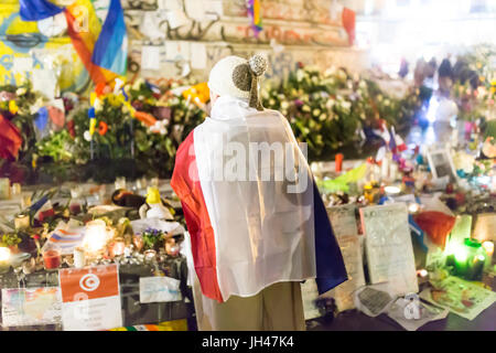 Un homme tenant un drapeau français en face de la République. Hommage spontané à des victimes des attaques terroristes à Paris le 13 novembre 2015. Banque D'Images