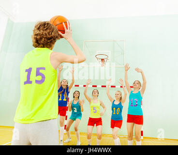 L'équipe de basket-ball d'Adolescent debout sous le panneau et défendre le cerceau d'un autre joueur Banque D'Images