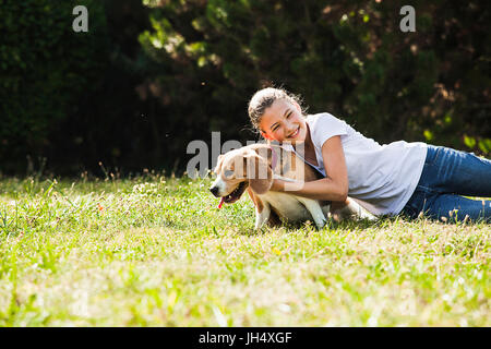 Adorable adolescente joue avec chien beagle dans le parc Banque D'Images