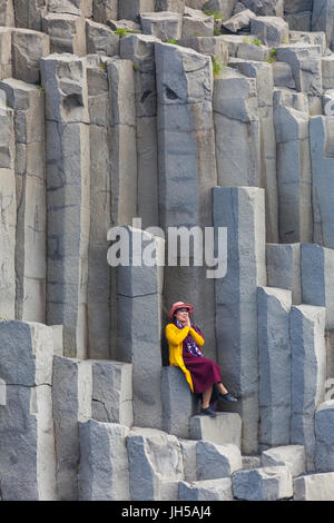 Pose de tourisme sur les grandes colonnes de basalte à plage Reynisfjara qui jouit en Islande Banque D'Images