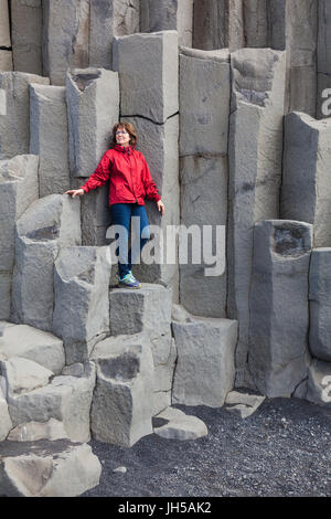 Pose de tourisme sur les grandes colonnes de basalte à plage Reynisfjara qui jouit en Islande Banque D'Images