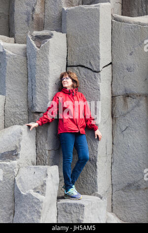 Pose de tourisme sur les grandes colonnes de basalte à plage Reynisfjara qui jouit en Islande Banque D'Images