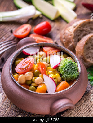 Dans une salade de légumes accueil conçu bol avec du pain sur la table en bois. Banque D'Images