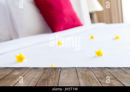 Table en bois vide point de vue en face de l'hôtel chambre avec lit et arrangement floral. Modèle pour la présentation du produit. L'espace vide. Banque D'Images