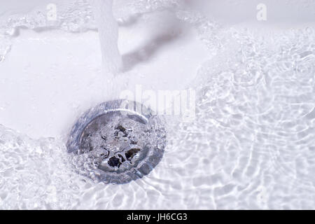 Fonctionnement de l'eau dans le drain. Salle de bain évier close up Banque D'Images
