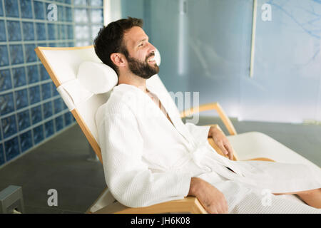 Handsome man relaxing in chair at spa Banque D'Images