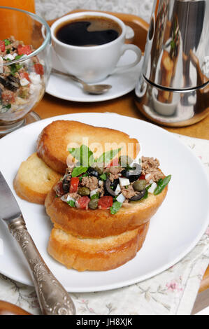 Petit déjeuner de pain frit avec des morceaux de thon avec l'oeuf, les cubes de tomates et les tranches d'olives, câpres avec une tasse de café, un pot de café sur un plateau Banque D'Images