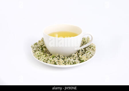 Thé fraîchement préparé avec tasse en porcelaine blanche décorée de fleurs fraîches. Banque D'Images