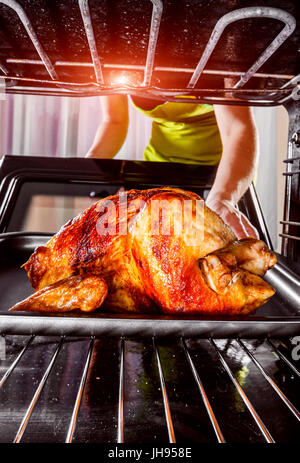 Ménagère prépare le poulet rôti au four, vue de l'intérieur du four. La cuisson au four. Jour d'action de grâce. Banque D'Images