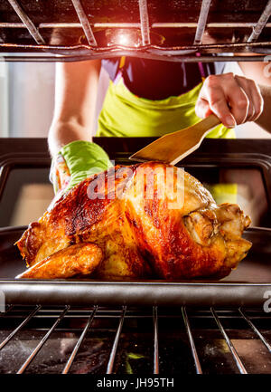 Ménagère prépare le poulet rôti au four, vue de l'intérieur du four. La cuisson au four. Banque D'Images