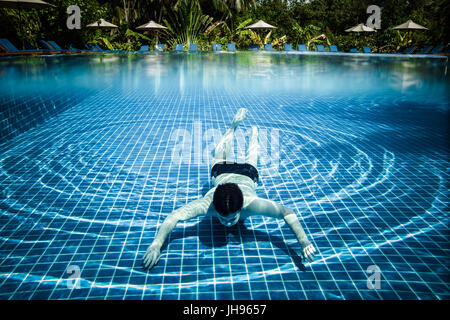 L'homme plonge dans une piscine donne sur l'eau et sous l'eau. Les Maldives. Banque D'Images