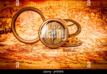 Vintage still life. Vintage loupe et d'une boussole se trouve sur une ancienne carte du monde en 1565. Banque D'Images