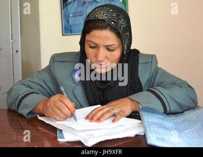 Tirin Kot, en Afghanistan. Le 13 juillet, 2017. Une policière afghane Masouma travaille à son bureau à Tirin Kot, la province d'Uruzgan, en Afghanistan, le 7 juillet 2017. Dans la société afghane, conservateur, en particulier dans la campagne ce qui concerne les femmes qui travaillent en dehors du foyer familial comme un "tabou." Mais une brave femme, Masouma, 45 ans, a échappé aux barrières culturelles et s'est joint à la force de police pour briser le tabou et montrer que les femmes peuvent rivaliser avec les hommes dans tous les domaines. Banque D'Images