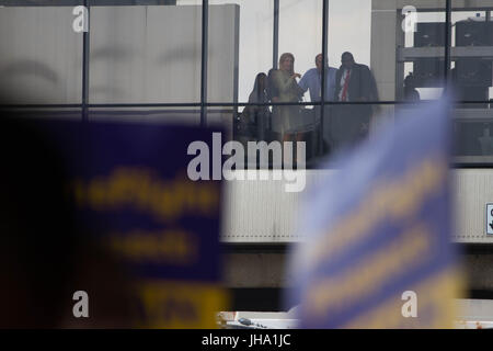 Philadelphie, USA. Le 13 juillet, 2017. American Airlines employés watch manifestants y compris les membres de l'Union internationale des employés de service, section locale 32BJ et alliés des syndicats et des groupes, rassemblement à l'Aéroport International de Philadelphie lors de la négociation du contrat avec American Airlines sous-traitants, le Jeudi, Juillet 13, 2017. Crédit : Michael Candelori/Alamy Live News Banque D'Images