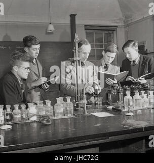 Années 1950, historique de l'après-guerre, England, UK, laboratoire de sciences à Mill Hill School, North London, England, UK, un britannique traditionnel et payant uniquement les garçons internat. L'image montre les garçons en prenant des notes que l'enseignant montre comment différents produits chimiques réagissent lorsque mélangé ensemble. Banque D'Images