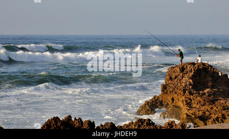 Pêcheur à la pêche Les pêcheurs locaux de rochers escarpés dans une mer de l'Atlantique à Oualidia littoral (El Jadida, Maroc), Casablanca-Settat Banque D'Images