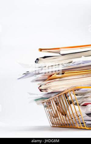 D'un angle bureau fil jaune ou dépôt dans le bac, empilés haut avec une pile malpropre de documents. Copie de l'espace sur fond blanc à gauche et ci-dessus. Banque D'Images