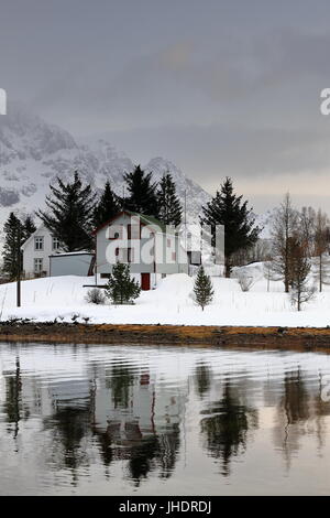 Blanc en bois Chalets sur l'île d'Vestpolloya Vestpollen Austnesfjorden village reflète dans Nordlia Slettlia-eaux et se monte sur l'arrière-plan. Centra Banque D'Images