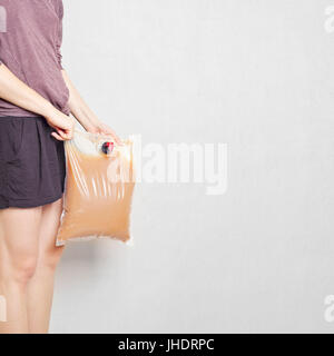 Girl holding sac plastique avec touchez plein de jus de pomme Banque D'Images