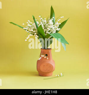 Le muguet en argile vase sur fond jaune Banque D'Images