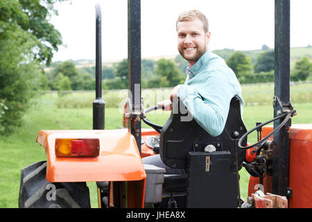 Portrait d'agriculteur assis sur le tracteur dans le champ, Banque D'Images