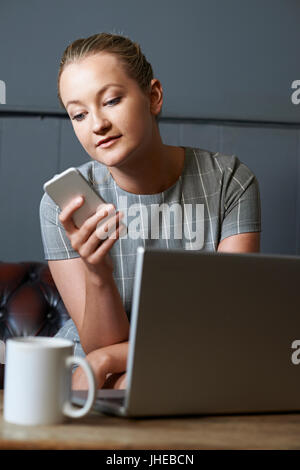 Woman Working On Laptop In Internet Cafe Banque D'Images