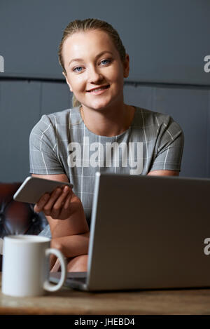 Portrait of Woman Working On Laptop In Internet Cafe Banque D'Images