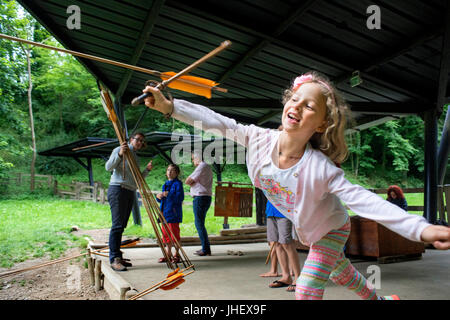 Parc préhistorique, Tarascon, espace muséographique, l'Ariège, France. Famille avec enfants apprennent à utiliser lanceur de javelot. Banque D'Images