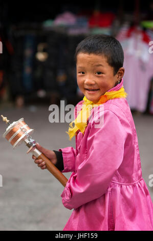 Un enfant tibétain fait tourner son moulin à prière dans les rues de Lhassa, près de temple de Jokhang, à Lhassa au Tibet. Pèlerins avec un moulin à prières Banque D'Images