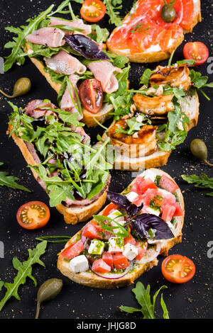 Brushetta définie pour le vin. Variété de petits sandwichs au jambon, tomates, fromage parmesan, basilic frais Banque D'Images