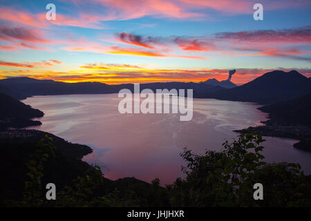 Le lever du soleil sur le lac Atitlan avec éruption volcan Fuego dans l'arrière-plan Banque D'Images