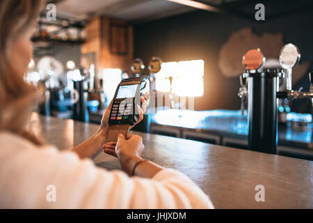 Cropped shot of woman paying bill à l'aide d'une carte de crédit au bar. Femme à l'usine de brasserie faisant des paiements sans numéraire. Banque D'Images