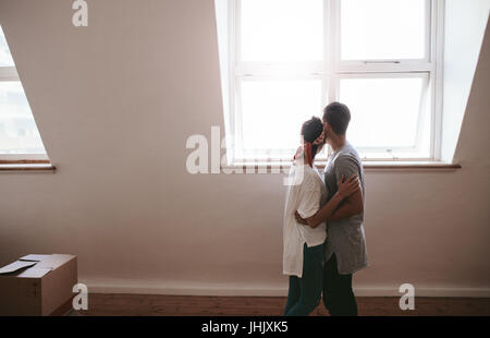 Jeune couple aimant déménagement dans un nouvel appartement. L'homme et la femme se tenant ensemble avec des cases sur le sol. Banque D'Images
