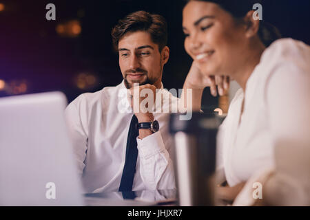 Business man and woman sitting at table and looking at laptop. Les gens d'affaires en attente à l'aide d'un salon d'aéroport d'un ordinateur portable. Banque D'Images