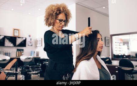 Styliste de cheveux des femmes travaillant sur un cheveux de femme. Coiffure femme servir son client au salon de coiffure. Banque D'Images