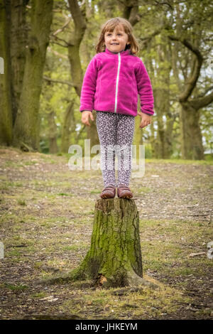 Petite fille s'apprête à sauter de l'arbre dans la forêt Banque D'Images