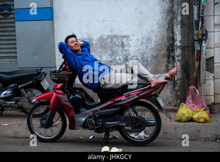 Un chauffeur de taxi moto vietnamienne repose assis sur sa moto à Ho Chi Minh Ville, Vietnam Banque D'Images