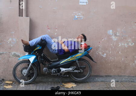 Un chauffeur de taxi moto vietnamienne repose assis sur sa moto à Ho Chi Minh Ville, Vietnam Banque D'Images