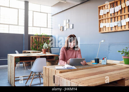 Smiling young man sur une tablette dans un bureau Banque D'Images