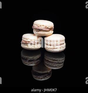 Macarons empilés isolé sur fond noir avec la réflexion. Dessert traditionnel français macarons Banque D'Images